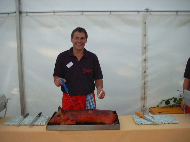 Mitarbeiter tranchiert ein Spanferkel am Buffet